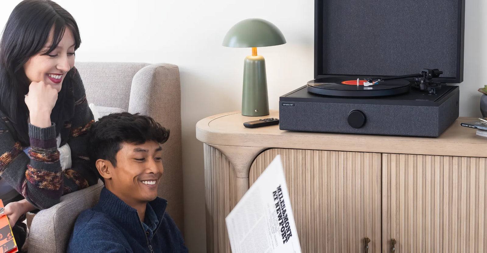 Un SpinPlay sobre un mueble de madera, junto a dos personas que miran un disco